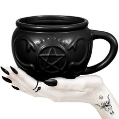 a hand holding a black mug with a pentagramil on it