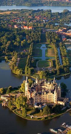 an aerial view of a large castle in the middle of a lake surrounded by trees