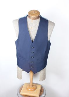 "ALL CLOTHING SALES ARE FINAL. How sharp is this vest, though? Wow. Navy polyester 5-button with perfect fit back. Back has satin coin pattern material. No smoke, mildew or damage. Please check measurements before purchasing. Measurements:  Chest: 34\" Length: 23\" Pair with many of the handsome ties available in the shop right now and save on shipping! I'm here to make you look good. What a fun item! Thank you for looking!" Formal Sleeveless Vest With Button Closure, Classic Single-breasted Sleeveless Vest, Tailored Sleeveless Vest With Button Closure, Classic Denim Vest With Button Closure For Work, Classic Denim Vest For Work, Fitted Vest With Snap Buttons For Work, Fitted Sleeveless Sweater Vest With Button Closure, Classic Tailored Vest With Button Closure, Blue Sleeveless Outerwear With Buttons