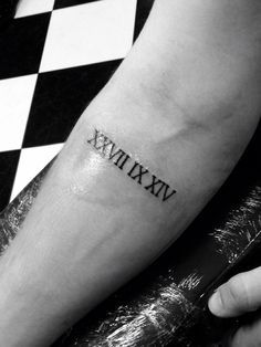 a person with a tattoo on their arm that says roman numerals in black and white