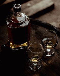 two glasses and a bottle sitting on top of a barrel