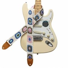 an electric guitar strap is decorated with crocheted flowers and beads, along with other accessories