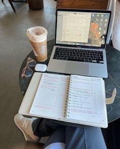 a laptop computer sitting on top of a glass table next to a cup of coffee