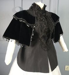 An opulent Victorian antique jacket dating to the 1880s ( the back definitely seems to be cut to accommodate a bustle, so i'm thinking 1880s ) - a nice gothic piece and an interesting alternative to the usual bustle mantle. Made in black ribbed silk faille, the torso fitted to a curvaceous hourglass, swelling at the back for a bustle and fastening with hooks at centre front. This part is sleeveless, the armholes finished with silk binding. The front is decorated with vertical black lace frills, Baroque Victorian Dress Costume, Victorian Black Outerwear For Costume Party, Victorian Historical Outerwear For Costumes, Victorian Style Historical Costume Outerwear, Victorian Outerwear With Historical Design For Costume, Vintage Costume Outerwear With Historical Design, Vintage Baroque Victorian Dress For Formal Occasions, Victorian Dress With Ruffles For Fall, Vintage Outerwear With Historical Design For Costume