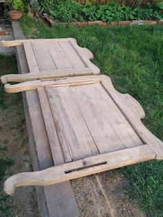 two benches made out of wood sitting in the grass next to some plants and flowers