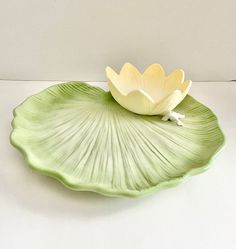 a white flower sitting on top of a green leaf shaped plate with water lily petals