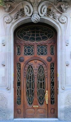 a large wooden door with ornate carvings on the front and side doors, in an old stone building