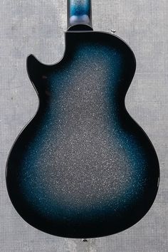 a black and blue guitar hanging on the side of a gray wall in front of a window