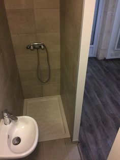 a bathroom with a sink, shower and wood flooring in the corner is shown