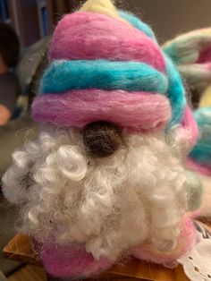 a close up of a stuffed animal with white hair and beard wearing a colorful hat