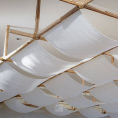 the ceiling is covered with white fabric and wooden poles, which are suspended from rafters