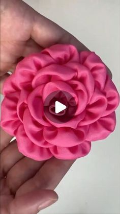 a pink flower being held in someone's hand with the video screen showing it