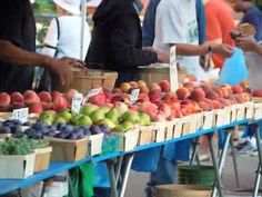 people are shopping at an outdoor market with fresh fruit