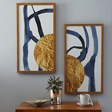 two paintings hang on the wall next to a table with a cup and saucer