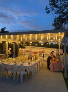 an outdoor dining area with tables and chairs set up for a birthday party at dusk