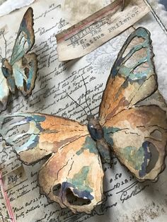 two butterflies sitting on top of an old piece of paper