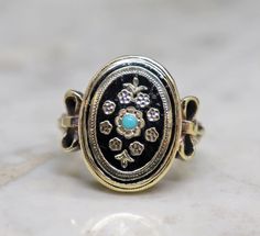 This is a Gorgeous Early Victorian 14k Gold Enamel and Turquose Ring.   The design is truly stunning with fleur de lis and floral accents on black enamel.   It has a turquoise in the center which really pops against the black enamel.   It has gorgeous bow accents on the shoulders.  The top measures 18.75mm across so it has nice size.    The enamel is in very good condition for its age with just minimal signs of wear under close inspection.    The size 5.5 ring weighs 5.5 grams.  It can be sized.  It isn't stamped but has been tested for 14k.   This ring has been checked by my jeweler and is ready to wear.   This is a true treasure from the past, so striking and the unique.  It is a highly collectible Victorian era ring and makes a great statement ring.  I have been selling jewelry for two Gold Enamel, Selling Jewelry, Black Enamel, Victorian Era, Statement Ring, Olympia, Rings Statement, Turquoise Ring, Jewelry Shop