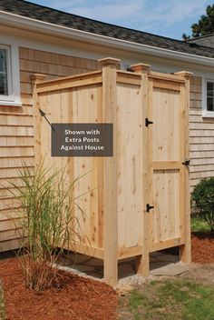 a wooden outhouse sitting in front of a house