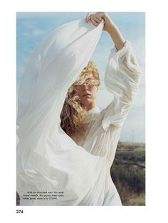 a woman in a white dress is posing with her hands on her head and arms behind her back