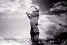 a black and white photo of a woman's body in the sky with clouds