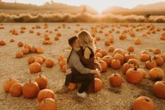 a man and woman sitting on top of pumpkins in the middle of a field