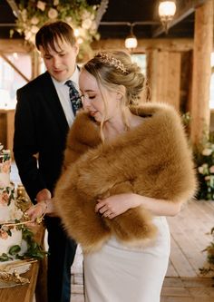 a bride and groom standing next to each other in front of a table with flowers