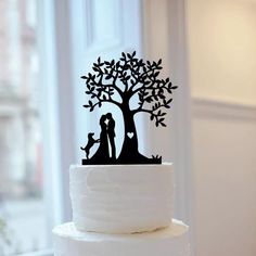 a wedding cake with a silhouette of a couple and dog under a tree