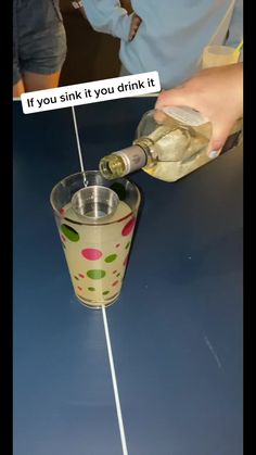 someone is pouring something into a glass with a straw and a bottle in it that says, if you sink it you drink it