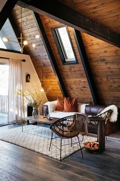 an attic living room with wood paneling and leather furniture, along with a rug on the floor