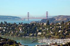 the golden gate bridge in san francisco, california is seen from atop a hill with boats on it