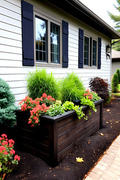 House facade with blue shutters and flowerbed bursting with red blooms and lush greenery, showcasing cheap simple front yard landscaping ideas. Front Small Yard Landscaping, Redoing Front Yard Landscaping Ideas, Curb Landscaping Ideas Street, Front Curb Appeal, How To Make Your Front Yard Look Better, Front Of House Landscape Ideas Farmhouse, Simple Landscaping Front Yard Low Maintenance Texas, Improve Curb Appeal Ranch, Cheap Ways To Increase Curb Appeal