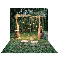 an outdoor area with lights and flowers on the grass, surrounded by wooden barrels filled with greenery