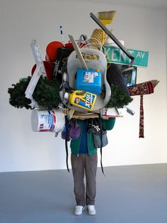 a person standing in front of a white wall with lots of items on top of it