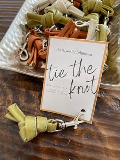 there is a sign that says tie the knot next to some paper clips on a table