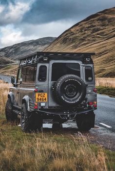 the jeep is parked on the side of the road in the field next to the mountain