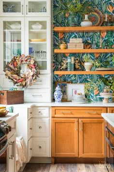 the kitchen is decorated with tropical wallpaper and wooden cabinets, along with white cupboards