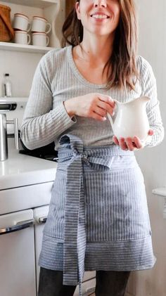 a woman is smiling while holding a pitcher