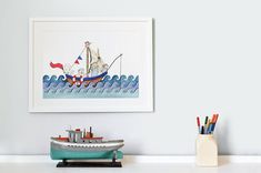 there is a small boat on the table next to some markers and pencils in front of it