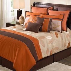 a bed with orange and brown comforters in a bedroom