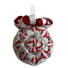 a red and white ornament hanging from a ribbon on a white background with silver beads