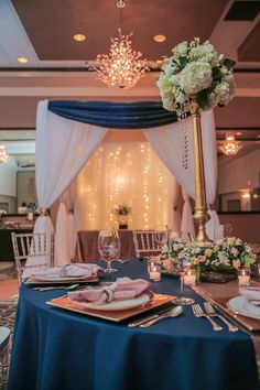 a table set up for a formal function with blue linens and white flowers on it