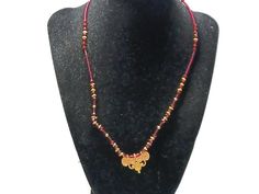 This necklace has a very small gold-tone pendant that lights up the whole necklace. It measures 1 inch wide by .5 inches long. The beads are a stunning red glass. This is perfect for someone who likes just a touch of drama in their dress. Spiritual Red Beaded Necklaces With Gold Beads, Spiritual Red Beaded Necklace With Gold Beads, Red Spiritual Necklace With Tiny Beads, Red Jewelry With Gold Beads For Gifts, Red Spiritual Jewelry With Gold Beads, Spiritual Red Jewelry With Gold Beads, Gift Amber Beaded Necklaces With Gold Beads, Amber Beaded Necklaces With Gold Beads For Gifts, Gift Amber Beaded Necklace With Gold Beads