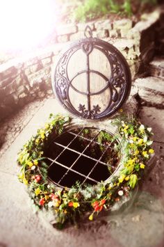 an outdoor planter with flowers on the ground next to it and a window in the middle