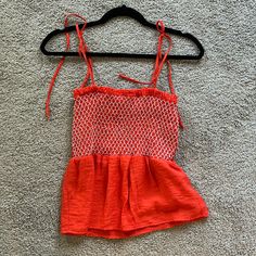 an orange and white dress hanging on a black hanger in the middle of carpet