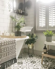 a white bath tub sitting next to a sink in a bathroom under a window with shutters