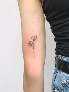 a woman's arm with a single flower tattoo on the left side of her arm