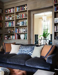 a living room filled with lots of bookshelves next to a couch and coffee table