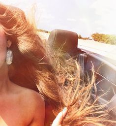 a woman is sitting in the back seat of a car with her hair blowing in the wind