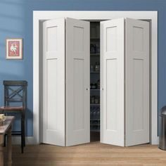 two white doors open in a room with blue walls and hardwood floors, along with a dining table