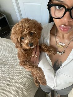 a woman holding a brown dog in her arms and looking at the camera while wearing glasses